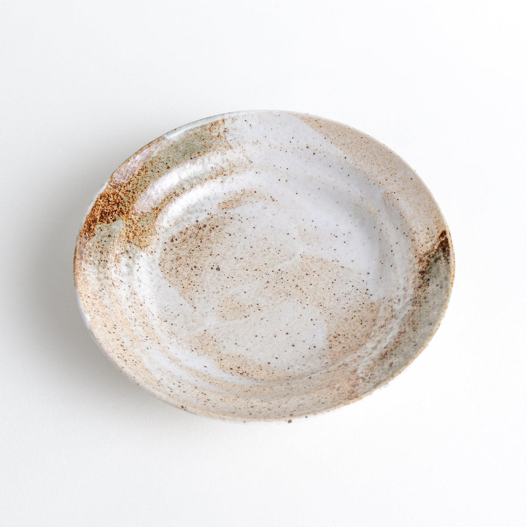 A salad plate with a speckled cream and brown glaze, featuring an earthy, organic design.