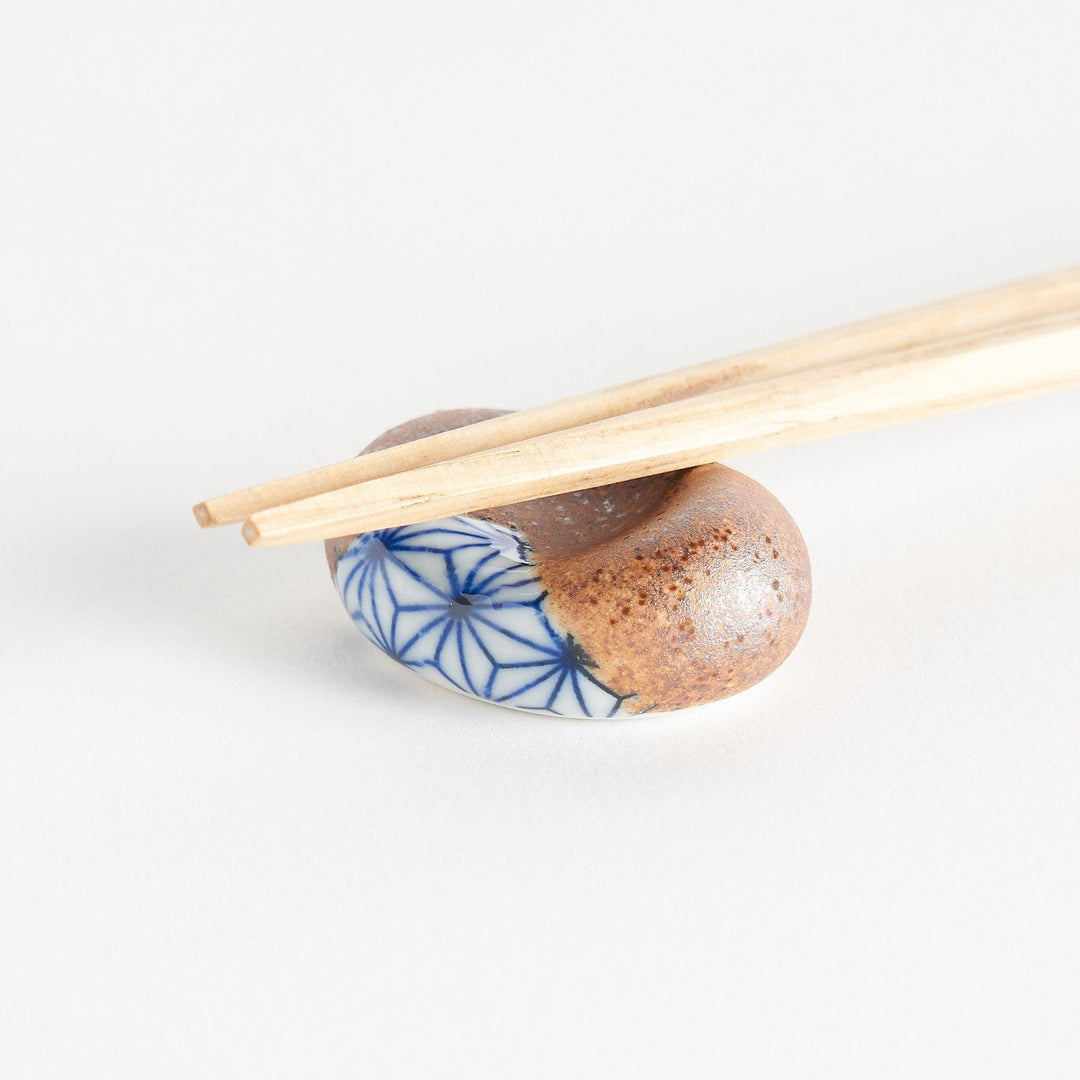 A brown and white rounded ceramic chopstick rest with a partial geometric pattern.