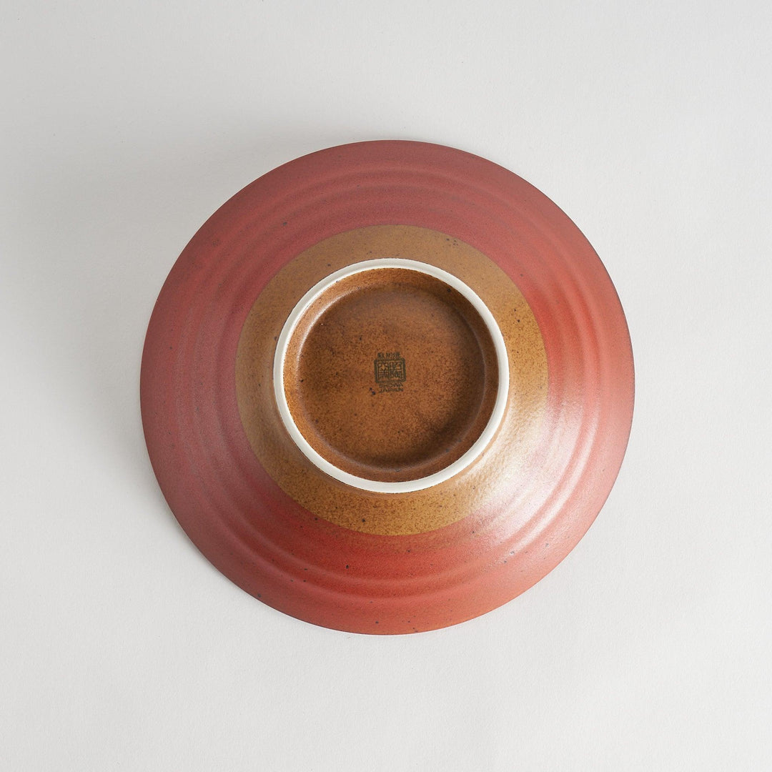 A shallow bowl featuring a red outer rim and a golden-brown interior with a fine radial pattern.