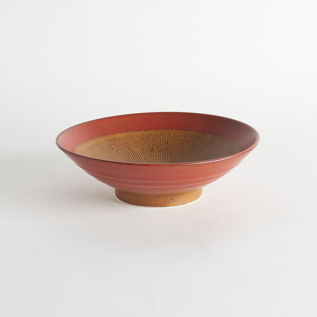 A shallow bowl featuring a red outer rim and a golden-brown interior with a fine radial pattern.