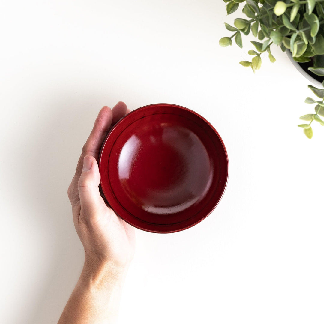 A lacquer bowl featuring a textured floral design and a wooden base. Available in black or red.