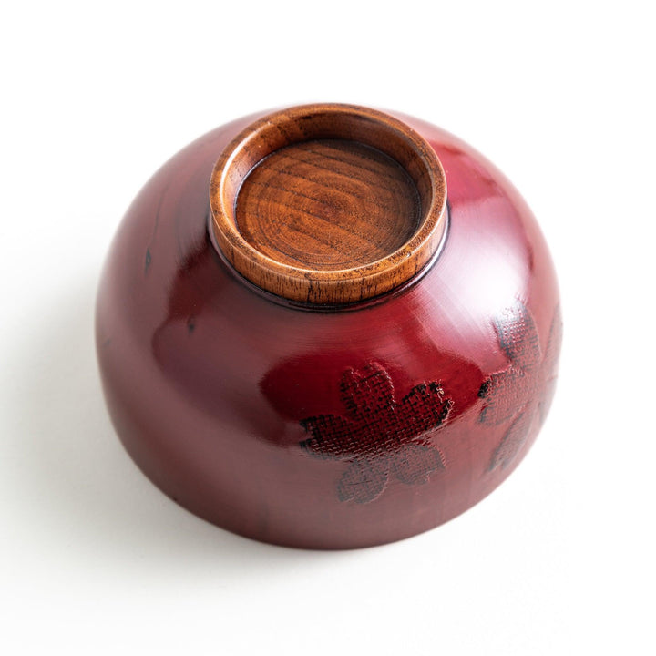 A lacquer bowl featuring a textured floral design and a wooden base. Available in black or red.