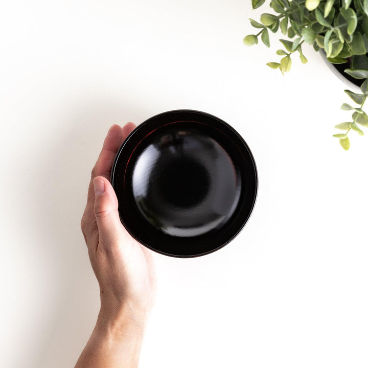 A lacquer bowl featuring a textured floral design and a wooden base. Available in black or red.