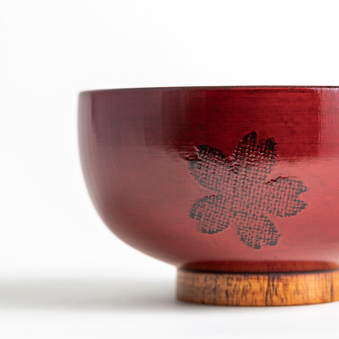 A lacquer bowl featuring a textured floral design and a wooden base. Available in black or red.