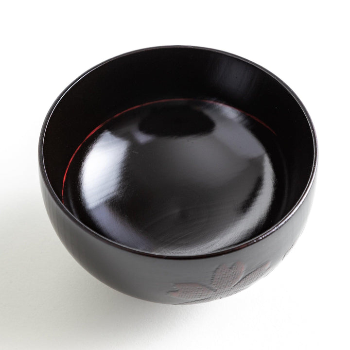 A lacquer bowl featuring a textured floral design and a wooden base. Available in black or red.