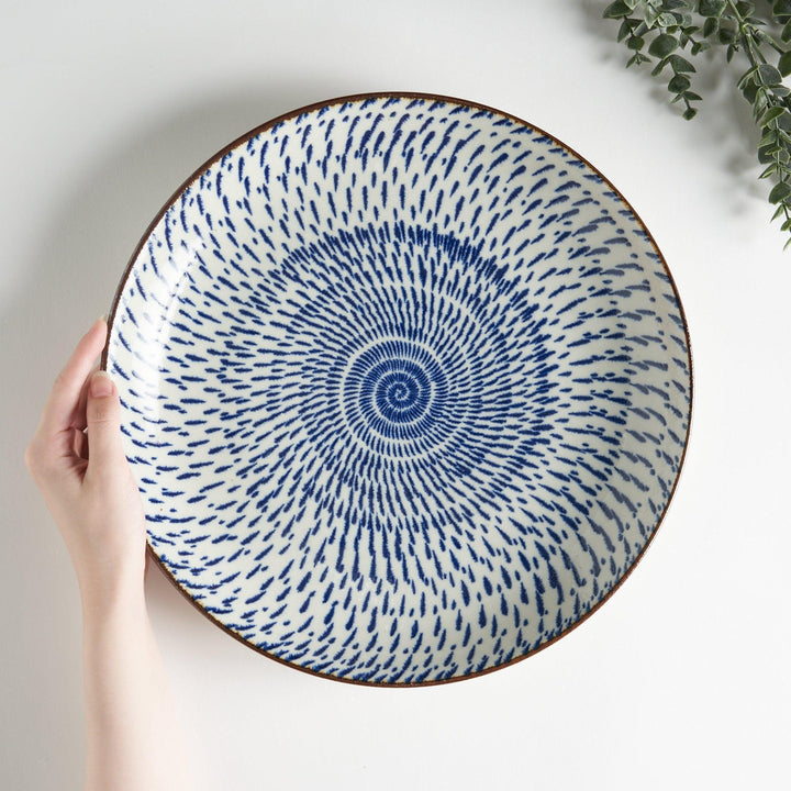 A round serving plate featuring a striking blue radial burst design from the center.