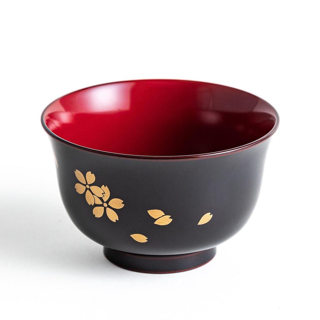 Traditional black lacquer bowl with red interior and gold cherry blossom motif.