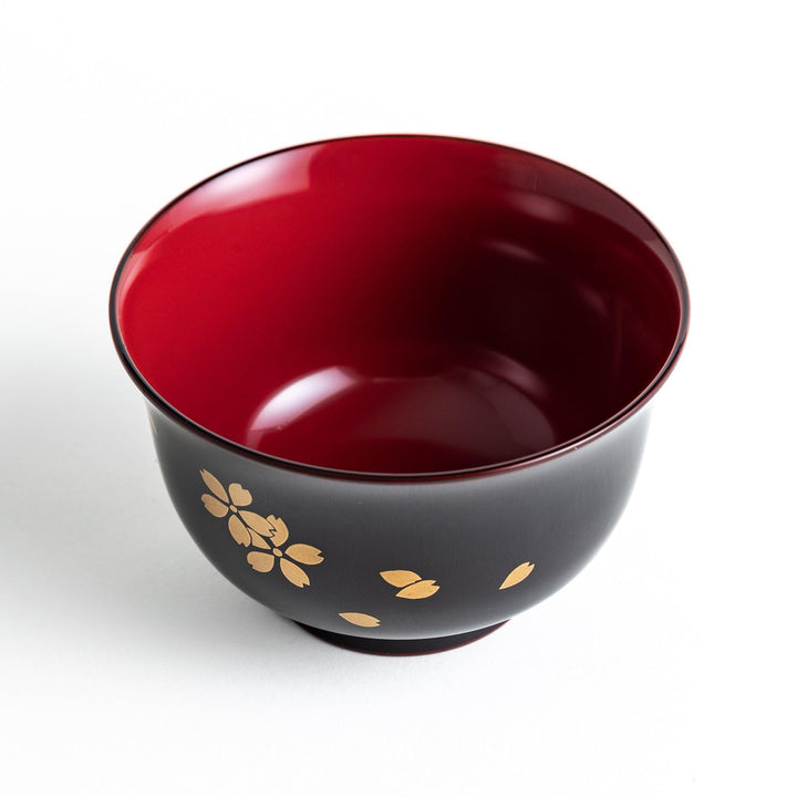 Traditional black lacquer bowl with red interior and gold cherry blossom motif.