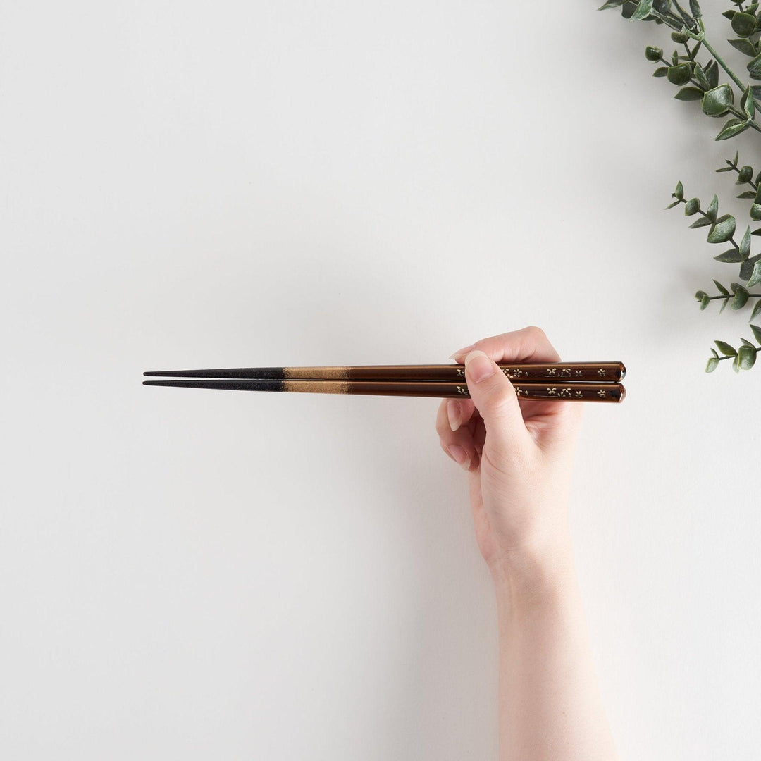 Elegant red and brown lacquered chopsticks adorned with delicate gold cherry blossom motifs, featuring a gradient of gold for added sophistication.