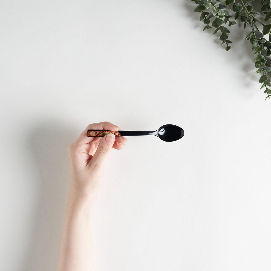 A set of two coffee spoons, one red and one black, featuring a detailed sakura pattern in gold on the handles.