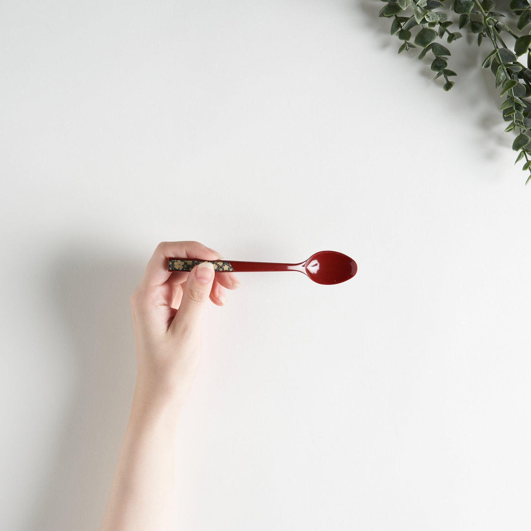 A set of two coffee spoons, one red and one black, featuring a detailed sakura pattern in gold on the handles.