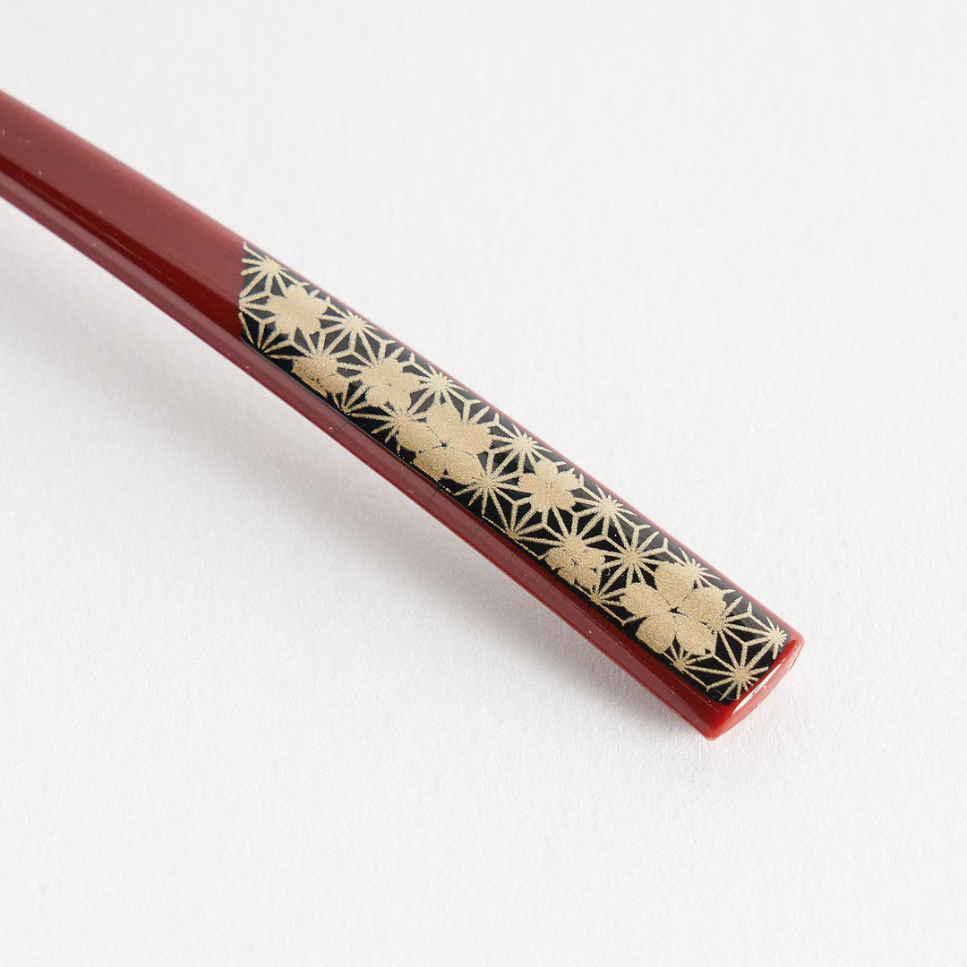 A set of two coffee spoons, one red and one black, featuring a detailed sakura pattern in gold on the handles.