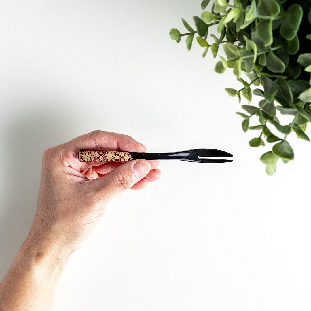 A set of two dessert forks, one red and one black, with a detailed gold sakura pattern on the handles.