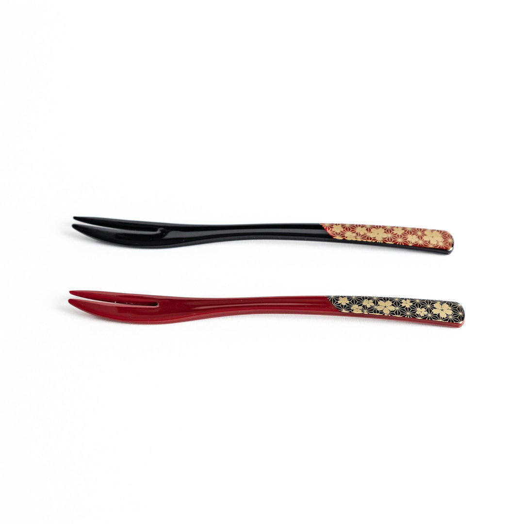 A set of two dessert forks, one red and one black, with a detailed gold sakura pattern on the handles.