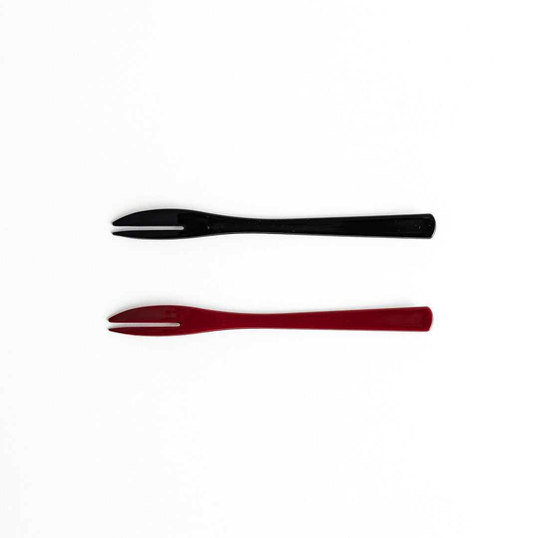 A set of two dessert forks, one red and one black, with a detailed gold sakura pattern on the handles.