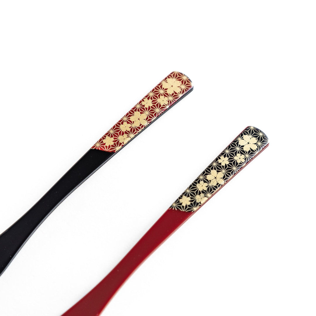 A set of two dessert forks, one red and one black, with a detailed gold sakura pattern on the handles.