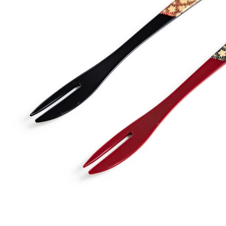 A set of two dessert forks, one red and one black, with a detailed gold sakura pattern on the handles.