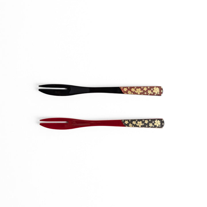 A set of two dessert forks, one red and one black, with a detailed gold sakura pattern on the handles.