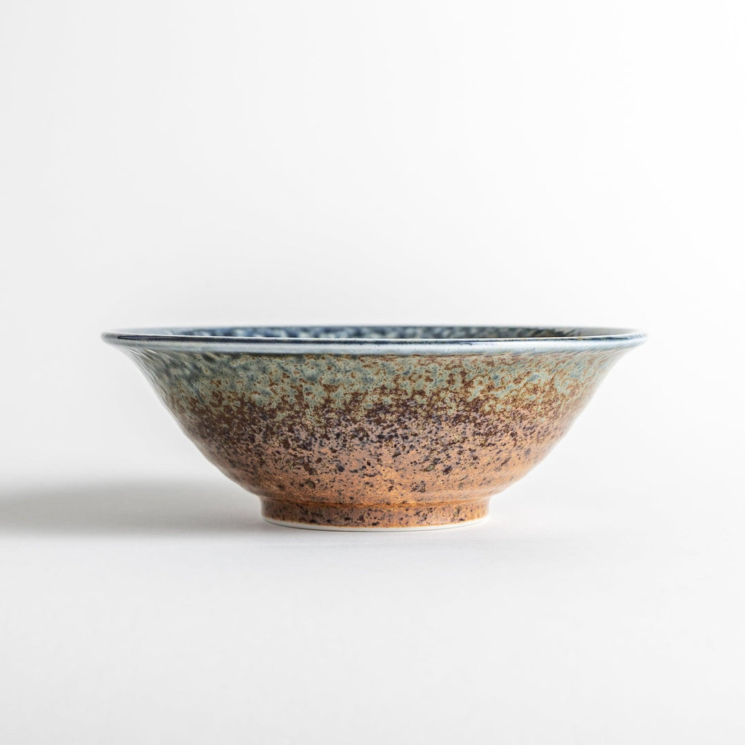 A deep ceramic bowl with a speckled glaze in shades of blue and brown, creating a textured, earthy appearance.