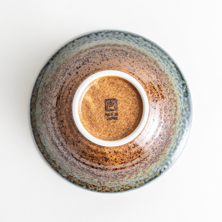 A deep ceramic bowl with a speckled glaze in shades of blue and brown, creating a textured, earthy appearance.