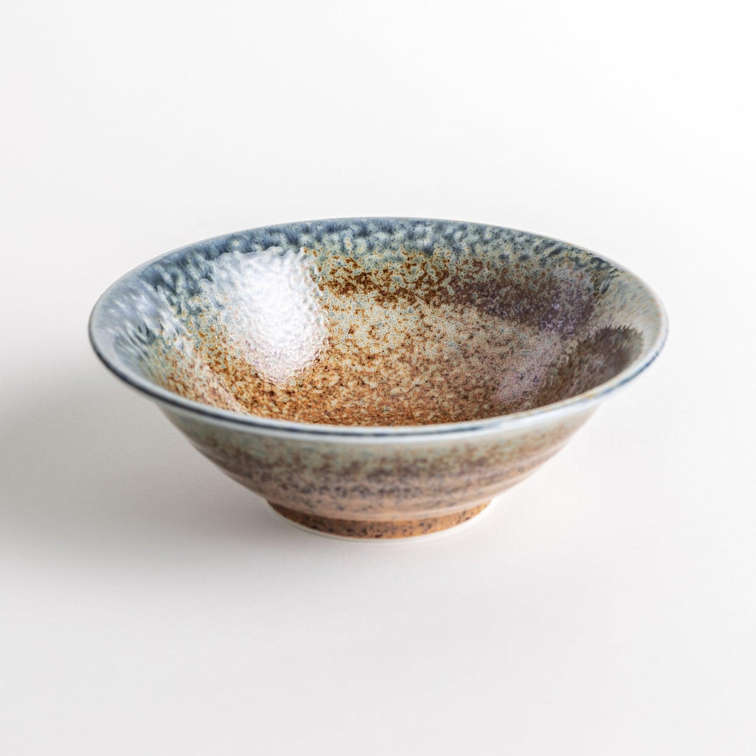 A deep ceramic bowl with a speckled glaze in shades of blue and brown, creating a textured, earthy appearance.