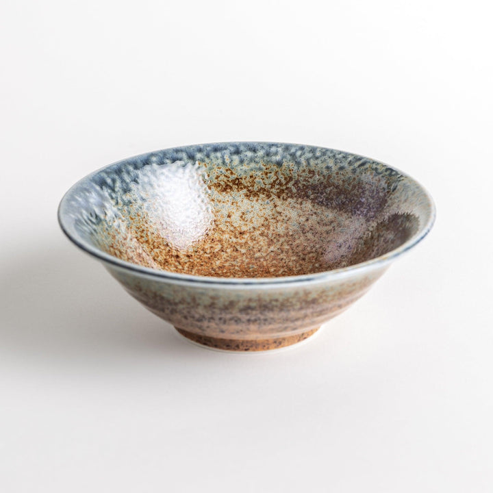 A deep ceramic bowl with a speckled glaze in shades of blue and brown, creating a textured, earthy appearance.