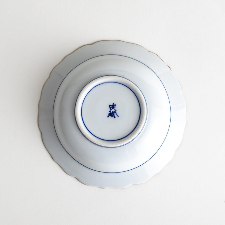 A ceramic bowl with a blue spiderweb-like pattern and scalloped edges.