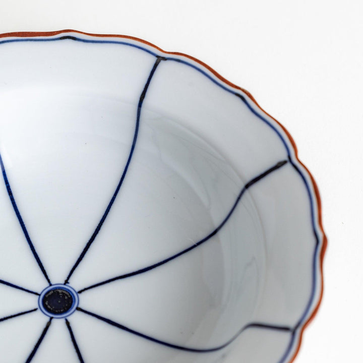 A ceramic bowl with a blue spiderweb-like pattern and scalloped edges.