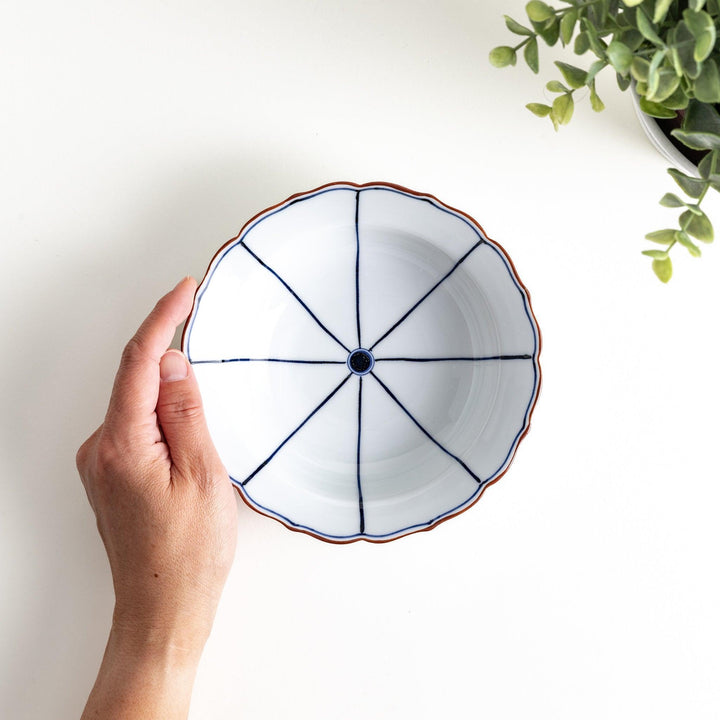 A ceramic bowl with a blue spiderweb-like pattern and scalloped edges.