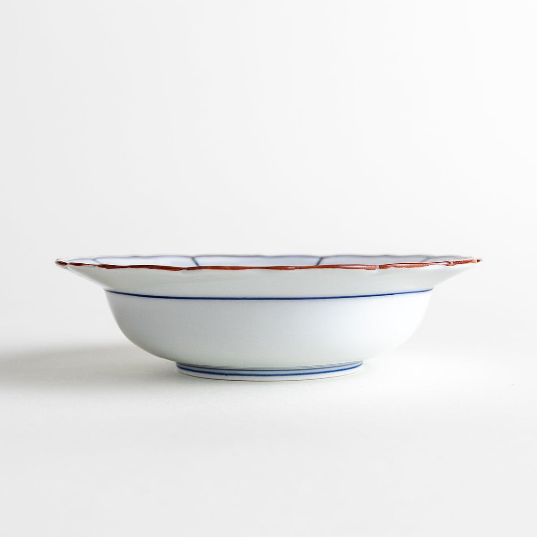 A ceramic bowl with a blue spiderweb-like pattern and scalloped edges.