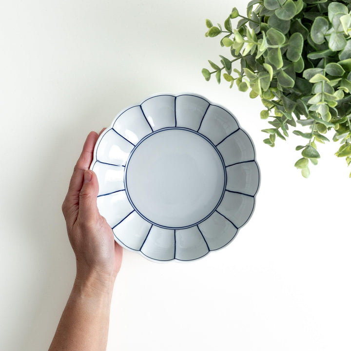 White cereal bowl with scalloped edges, featuring thin blue and red lines forming a petal-like design.