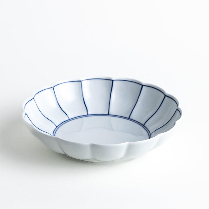 White cereal bowl with scalloped edges, featuring thin blue and red lines forming a petal-like design.