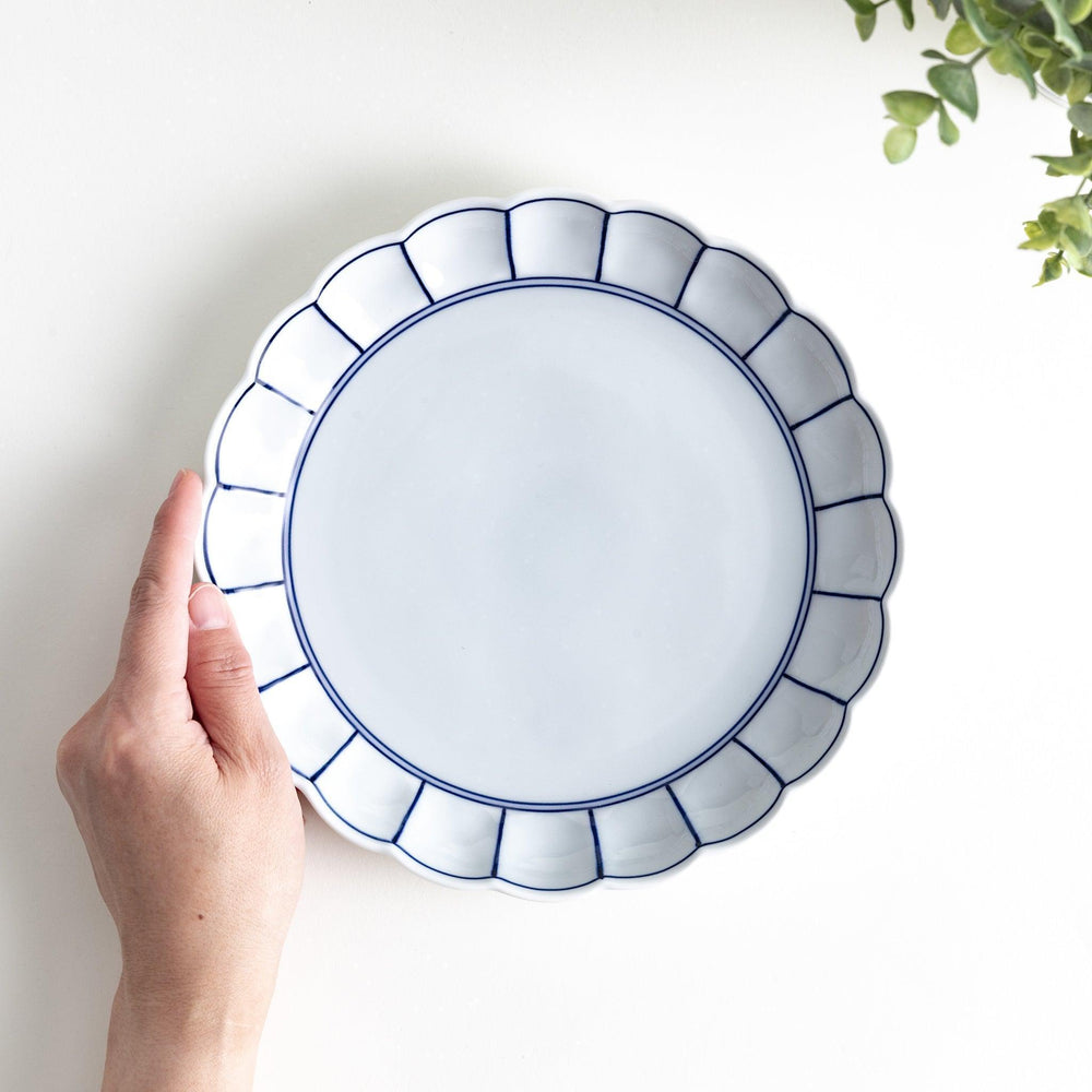 White salad plate with scalloped edges, outlined in a thin blue or red line.