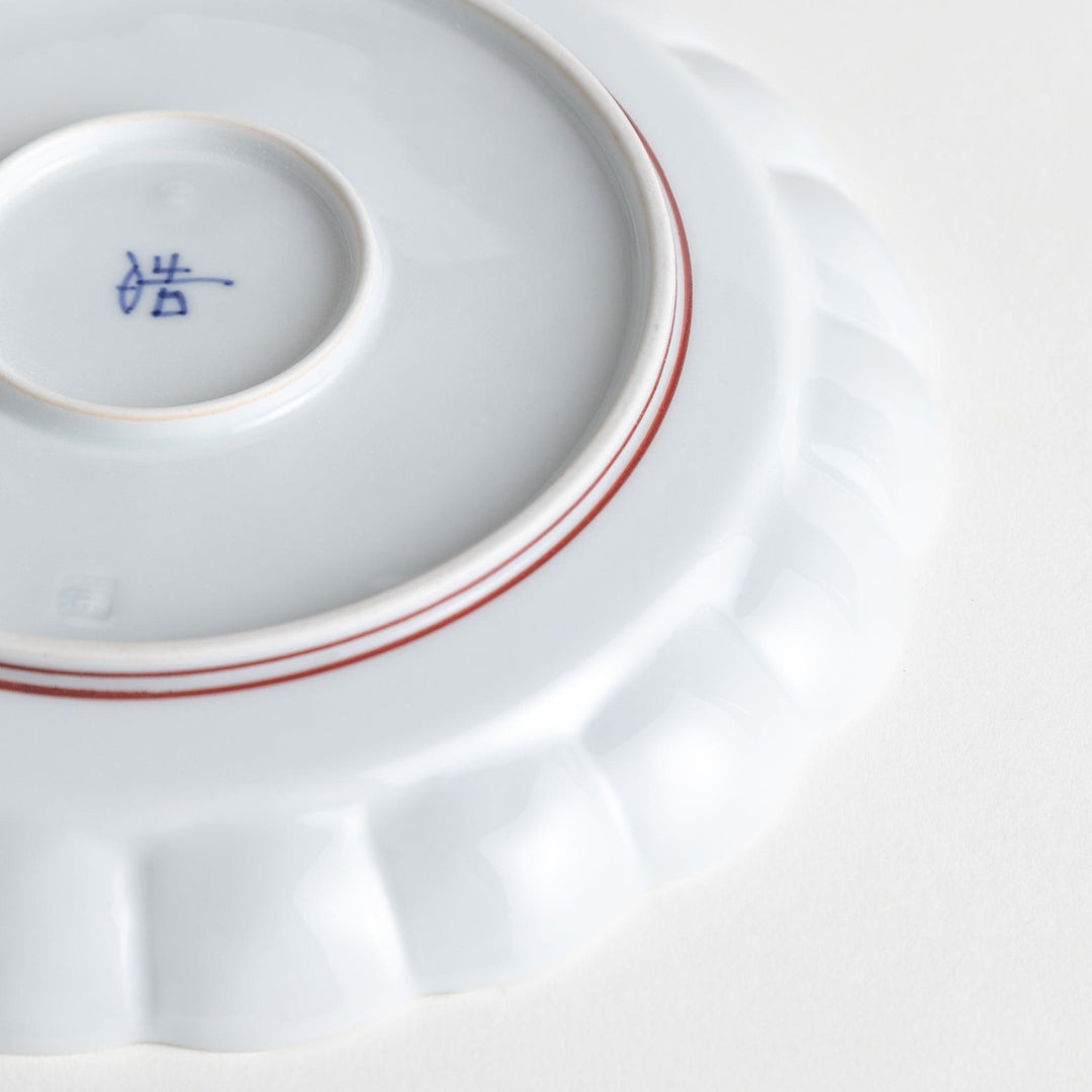 White salad plate with scalloped edges, outlined in a thin blue or red line.