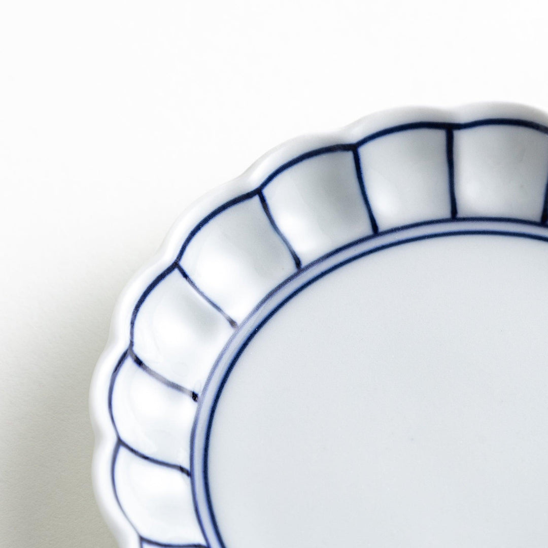 White sauce dish with scalloped edges, outlined in a thin blue or red line.