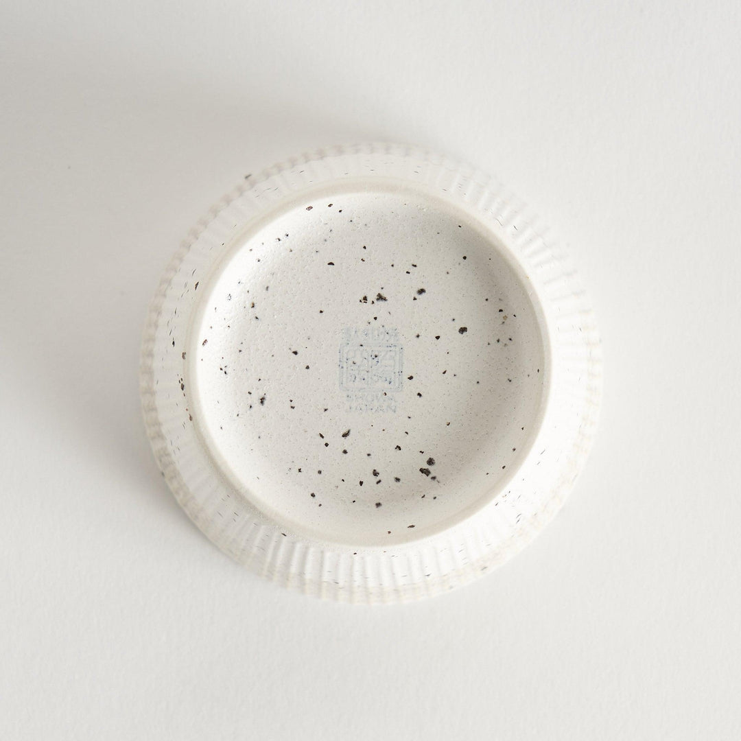 A small, off-white ceramic cup with a ribbed texture and subtle speckled design.