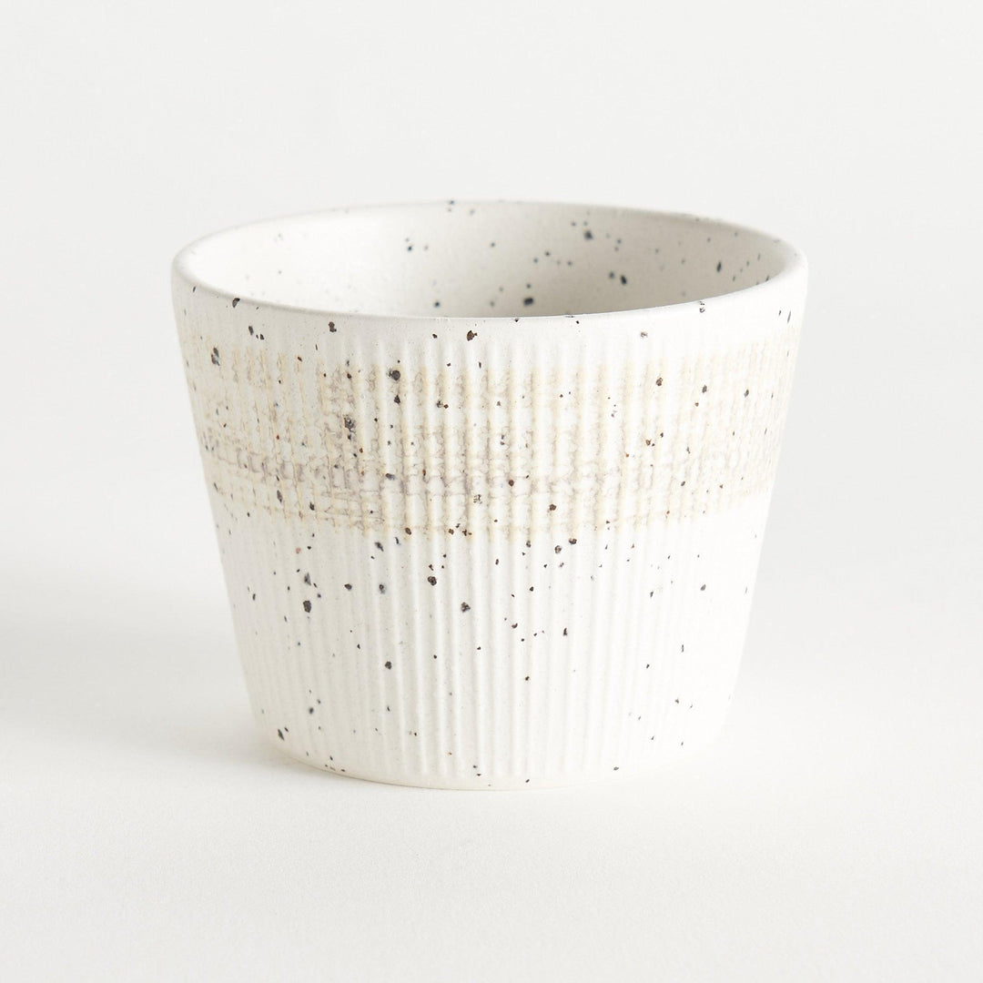 A small, off-white ceramic cup with a ribbed texture and subtle speckled design.