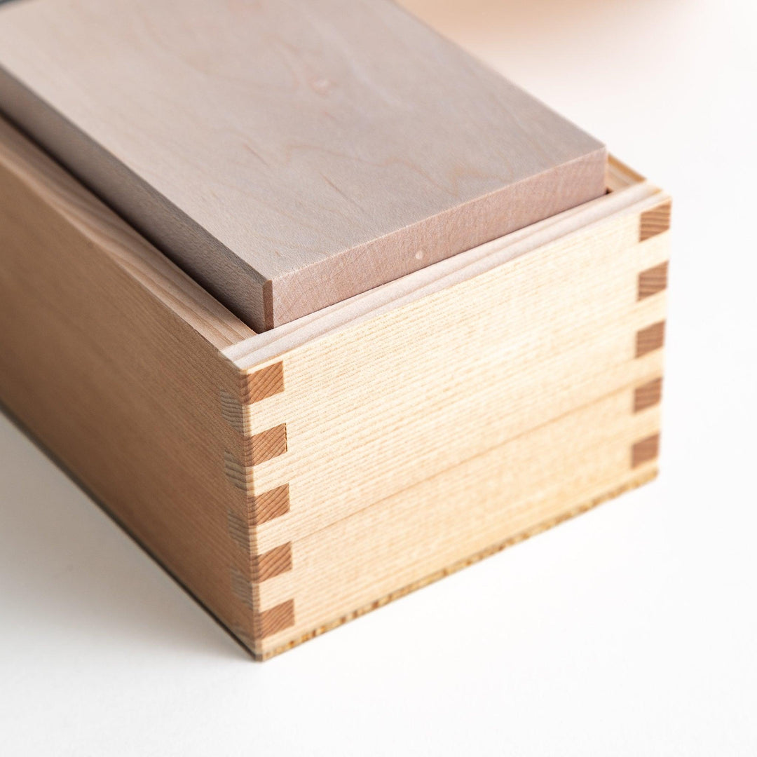 A small wooden box with a sliding drawer and lid, designed for shaving katsuobushi (dried bonito), with a colorful packaging box featuring traditional Japanese artwork.