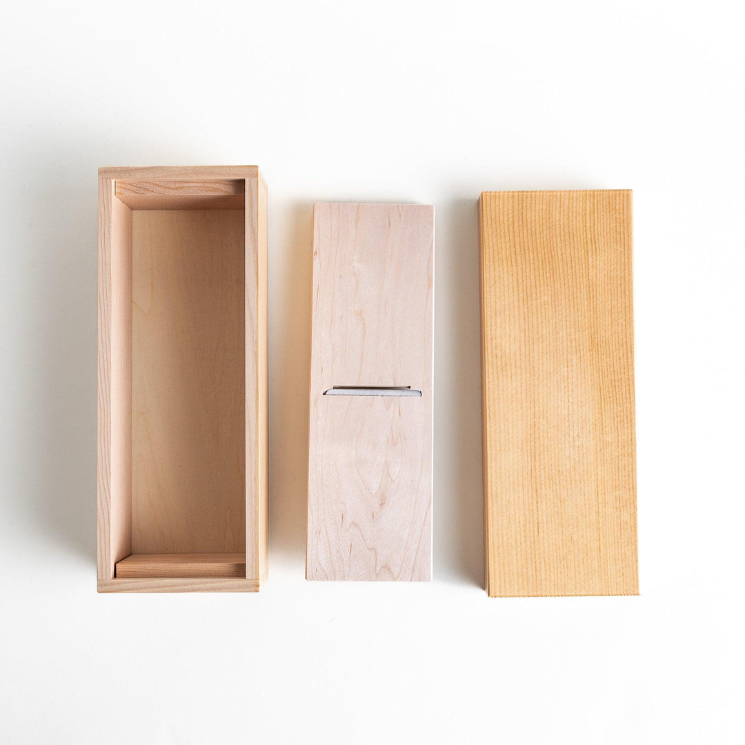 A small wooden box with a sliding drawer and lid, designed for shaving katsuobushi (dried bonito), with a colorful packaging box featuring traditional Japanese artwork.