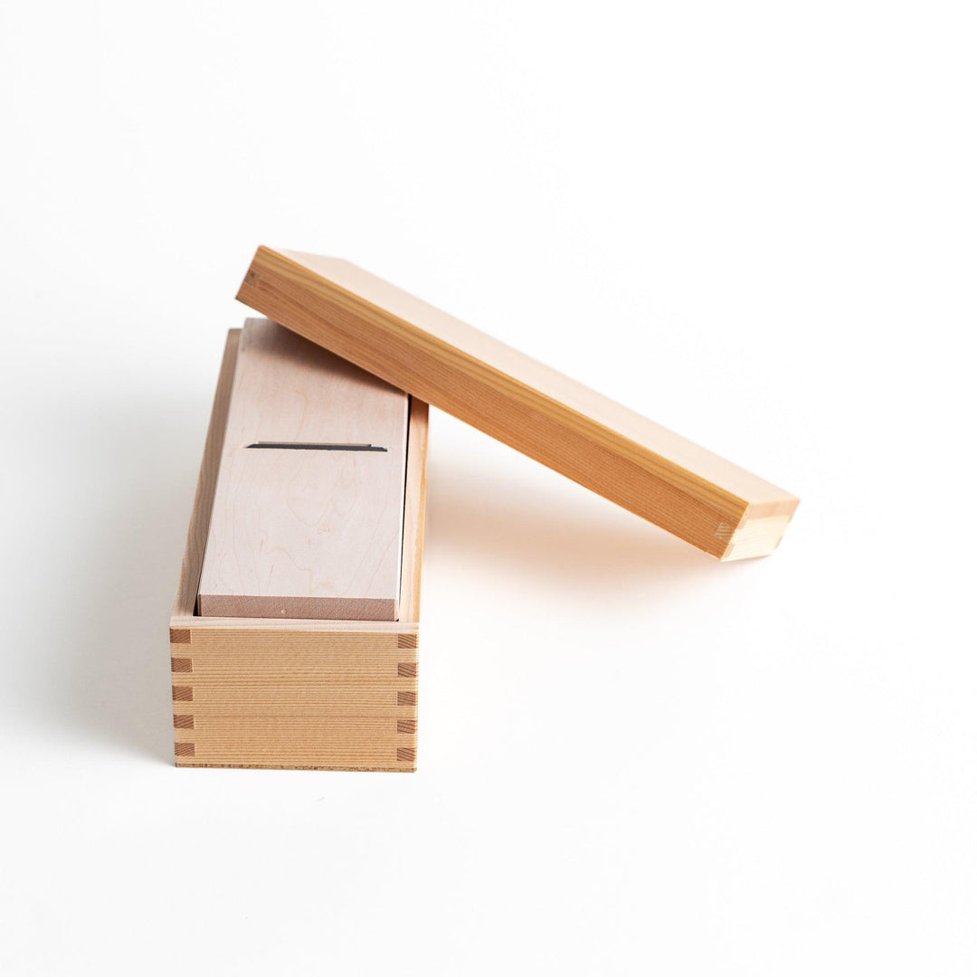 A small wooden box with a sliding drawer and lid, designed for shaving katsuobushi (dried bonito), with a colorful packaging box featuring traditional Japanese artwork.