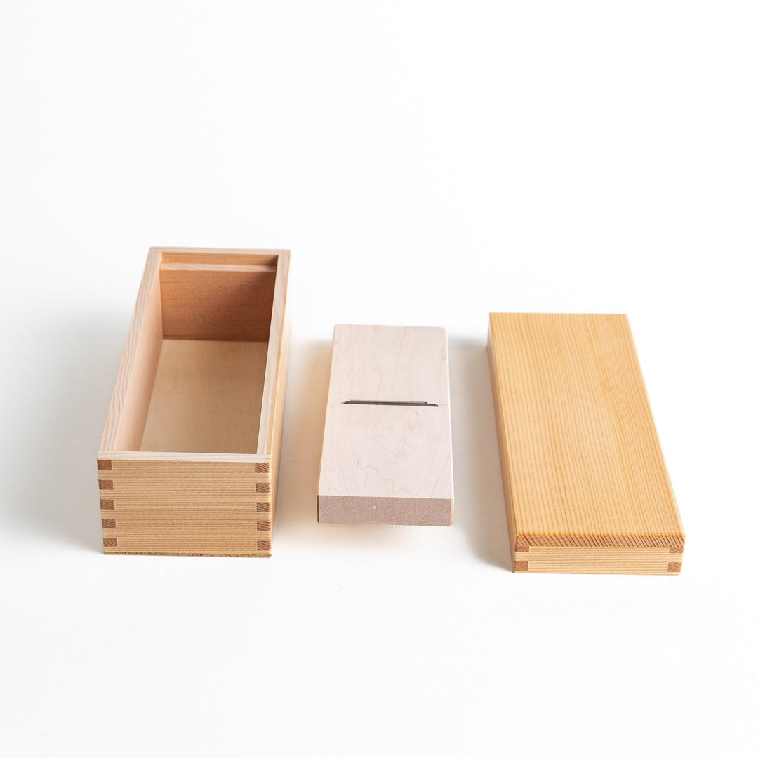 A small wooden box with a sliding drawer and lid, designed for shaving katsuobushi (dried bonito), with a colorful packaging box featuring traditional Japanese artwork.