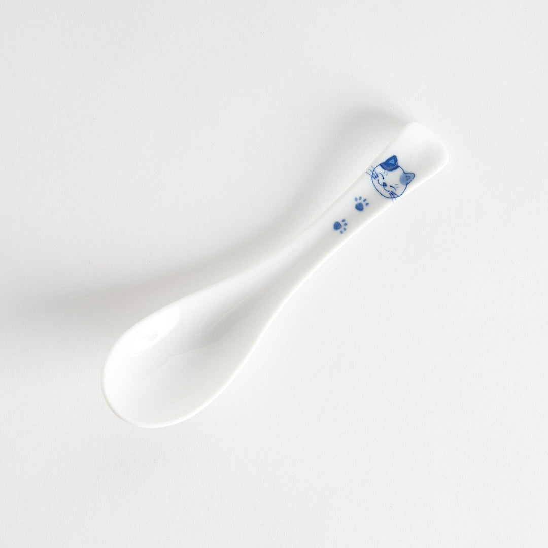 A white porcelain spoon with a blue cat face and paw prints on the handle.