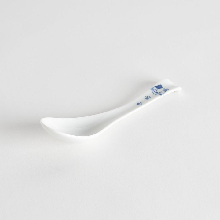 A white porcelain spoon with a blue cat face and paw prints on the handle.