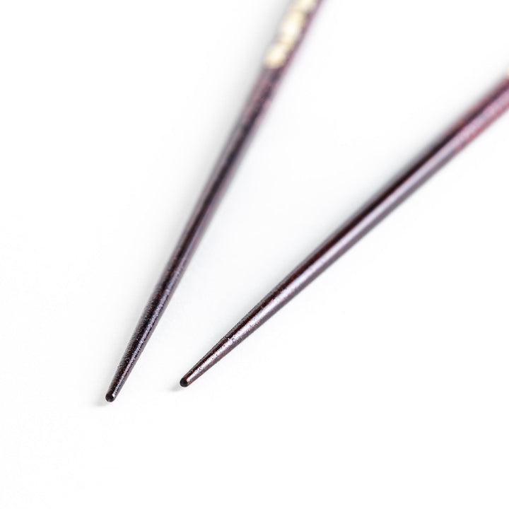 Two pairs of chopsticks, one in deep purple and the other in red, each decorated with subtle gold accents and a speckled finish.