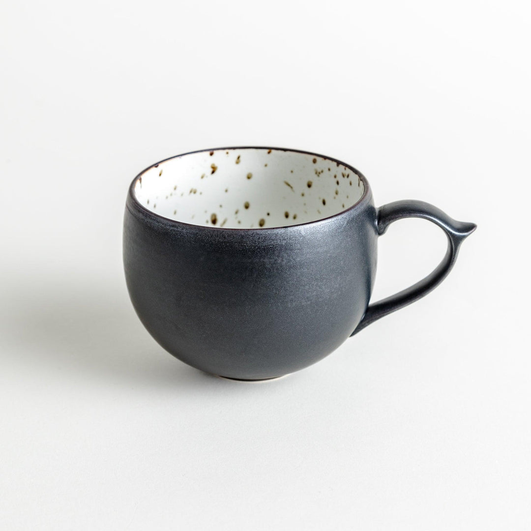 Ceramic mugs, one in matte black and the other in speckled white, with delicate curved handles.