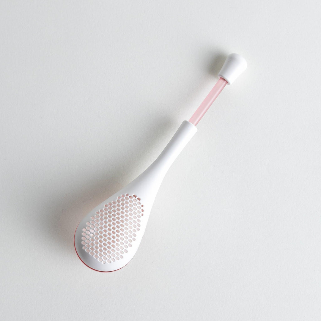 – A modern, white maraca-shaped spice sifter with a textured surface and a pink handle.