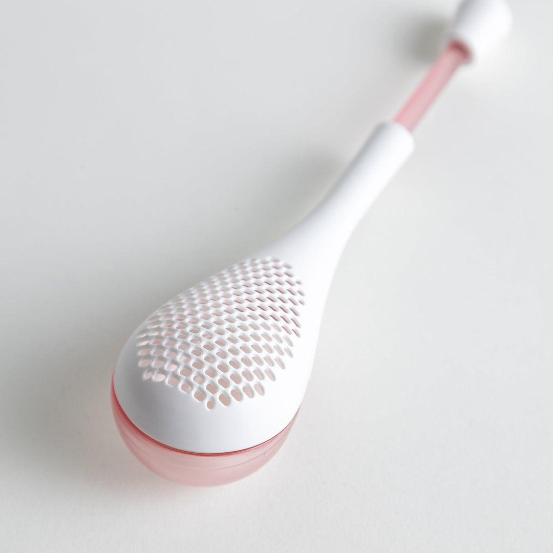 – A modern, white maraca-shaped spice sifter with a textured surface and a pink handle.