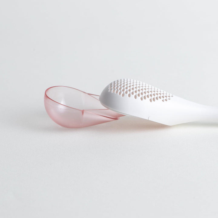 – A modern, white maraca-shaped spice sifter with a textured surface and a pink handle.