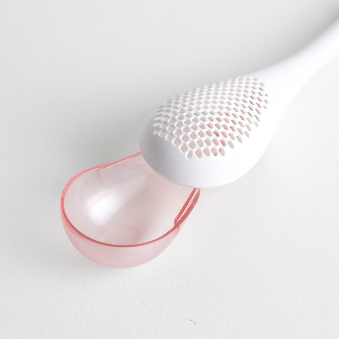 – A modern, white maraca-shaped spice sifter with a textured surface and a pink handle.