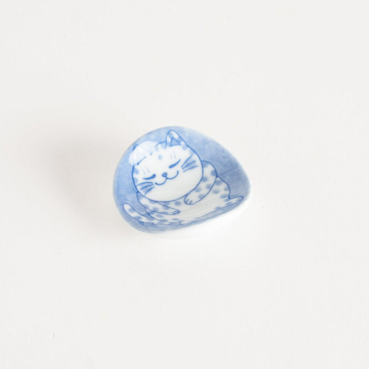 A round ceramic chopstick rest with a smiling, spotted cat illustration in blue.